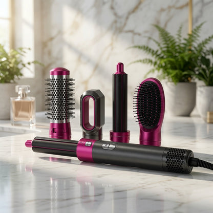 A hair styling tool set with a black and magenta cylindrical device and several attachments, arranged on a marble countertop with plants and a perfume bottle in a bright bathroom-like setting.